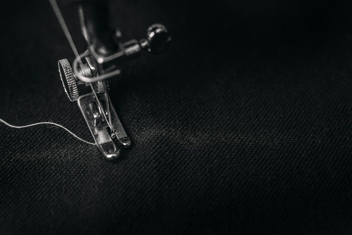 Sewing machine presser foot with thread on black cloth